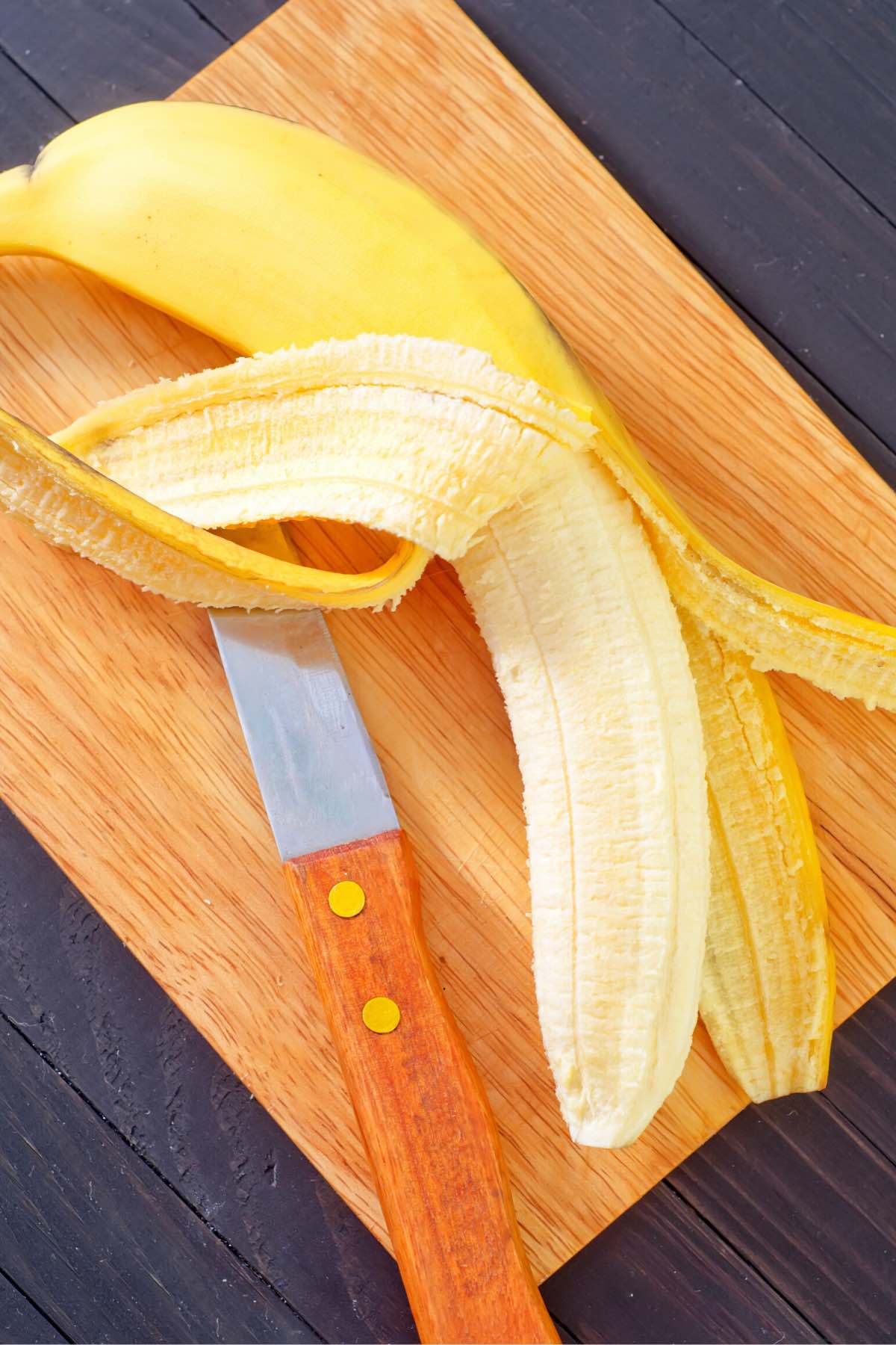 Peeling and slicing a ripe banana on a cutting board