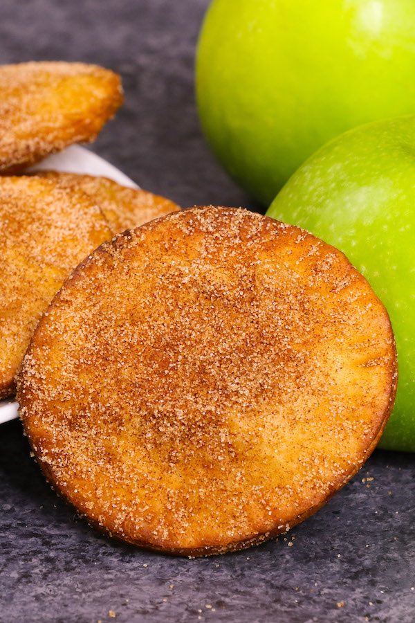 Apple hand pies dusted in cinnamon sugar with Granny Smith apples in the background