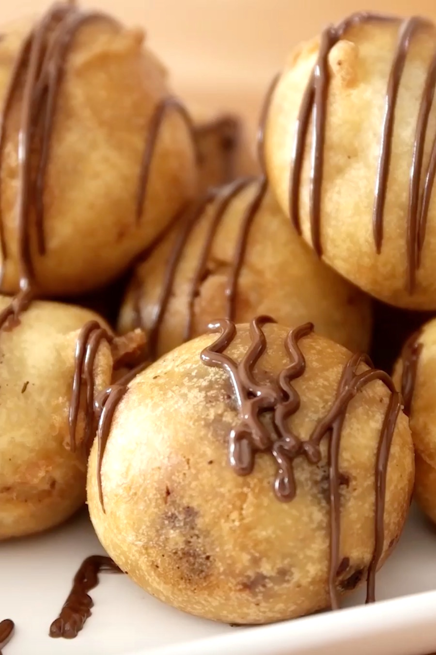 Closeup of fried cookie dough bites being drizzled with melted chocolate