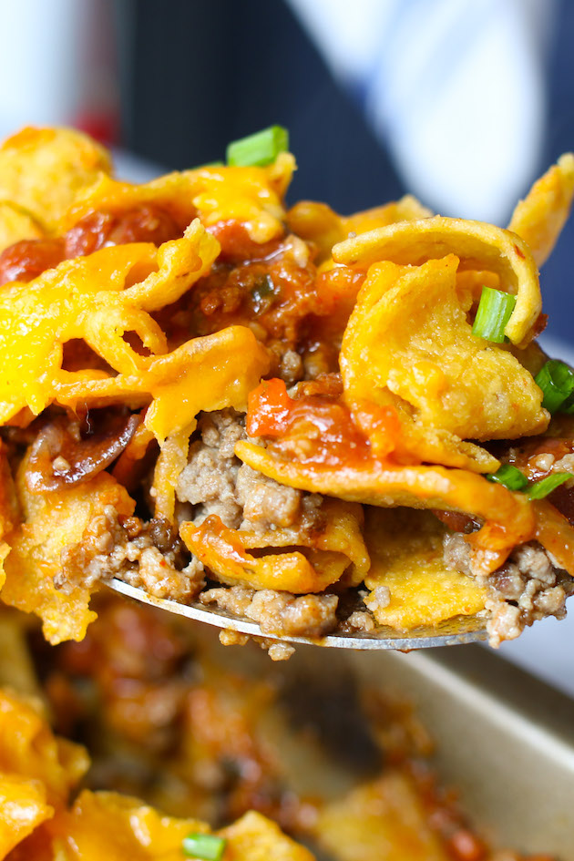 Closeup of a forkful of authentic Frito Pie showing delicious layers of corn chips, beef chili and cheese