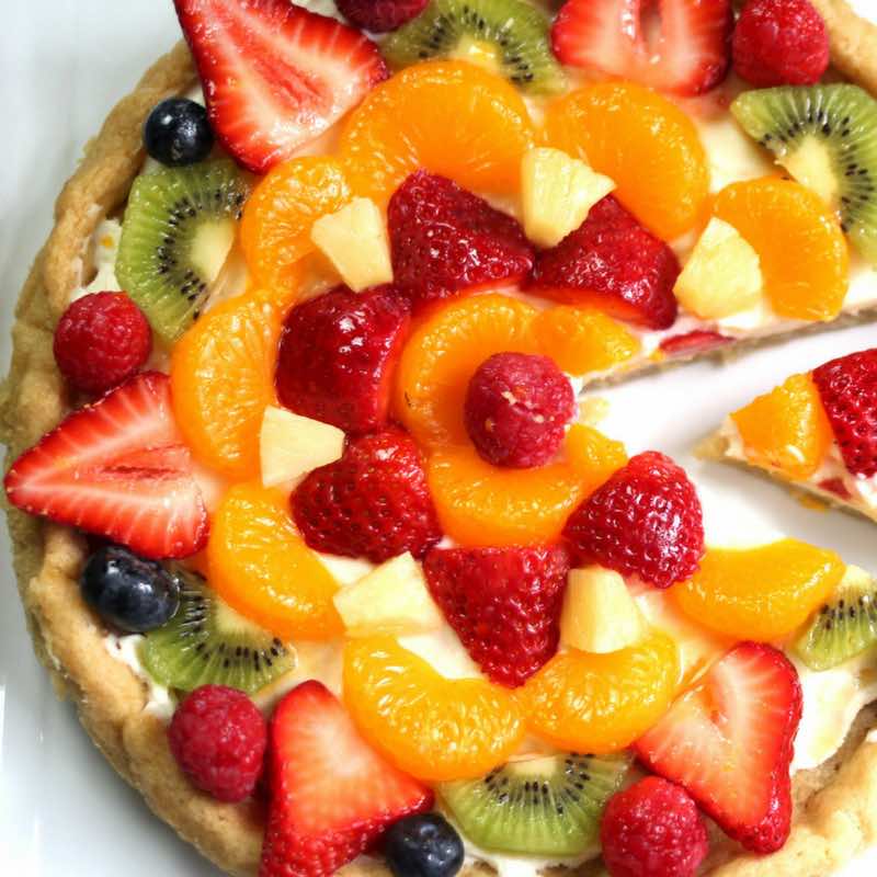 Fruity Pizza - The easiest and most unbelievably beautiful fruit pizza or fruity sugar cookie cake has a soft sugar cookie crust and smooth creamy filling, topped with fresh fruits. All you need is a few simple ingredients: refrigerated sugar cookie dough, cream cheese, sugar, vanilla extract and fruit of your choice! A simple dessert you whole family will be obsessed with. It takes only 20 minutes to make. Perfect for holiday party dessert such as Easter, Mother’s Day, Father’s Day or birthdays. Quick and easy, vegetarian. Video recipe. | tipbuzz.com