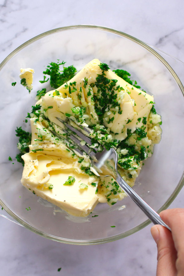 Combining butter, garlic, parsley and lemon juice in a bowl when making homemade garlic butter