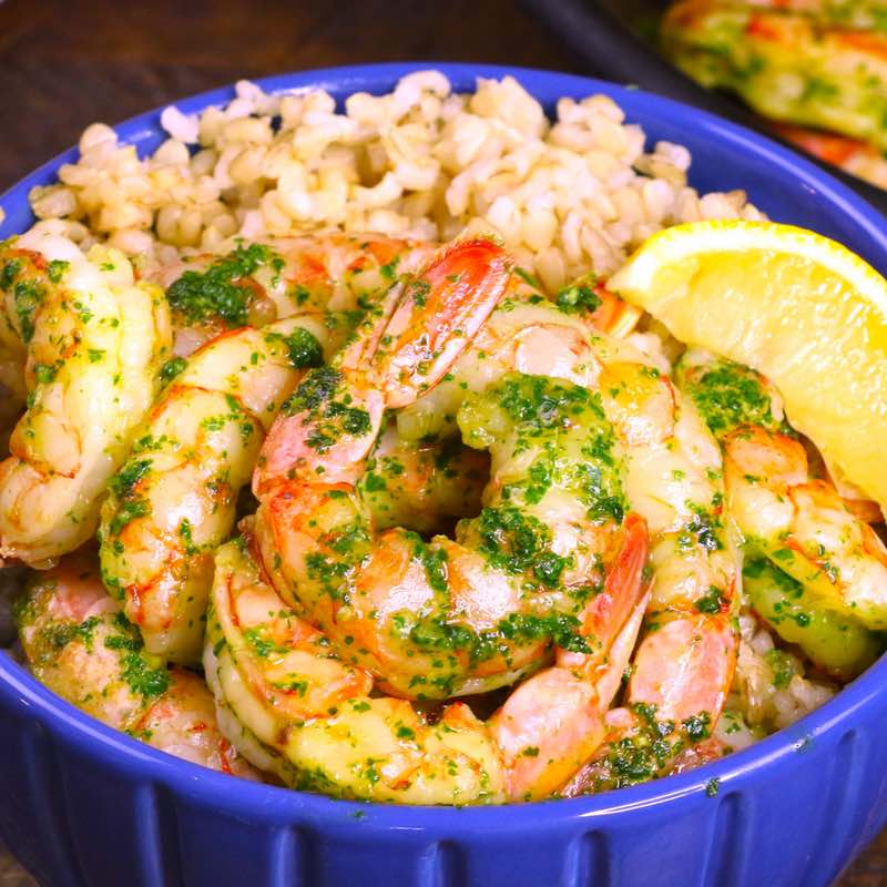 This photo shows garlic butter shrimp served on a bed of rice in a bowl