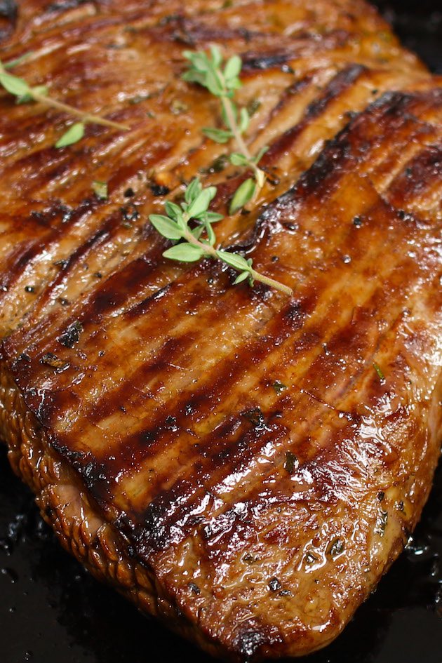 A closeup photo of a piece of grilled flank steak that's tender and juicy on the inside and evenly browned on the surface