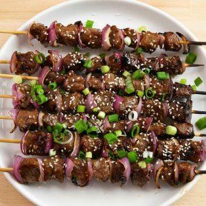 Grilled Garlic Beef Kabobs – Incredibly delicious beef skewers that are so easy to make! Nothing is better than these kabobs to serve on a warm summer day! All you need is some simple ingredients: steak, soy sauce, garlic, red onions, green onions, sesame seeds, sugar, ginger and oil. So Good! Quick and easy recipe, video recipe. | Tipbuzz.com