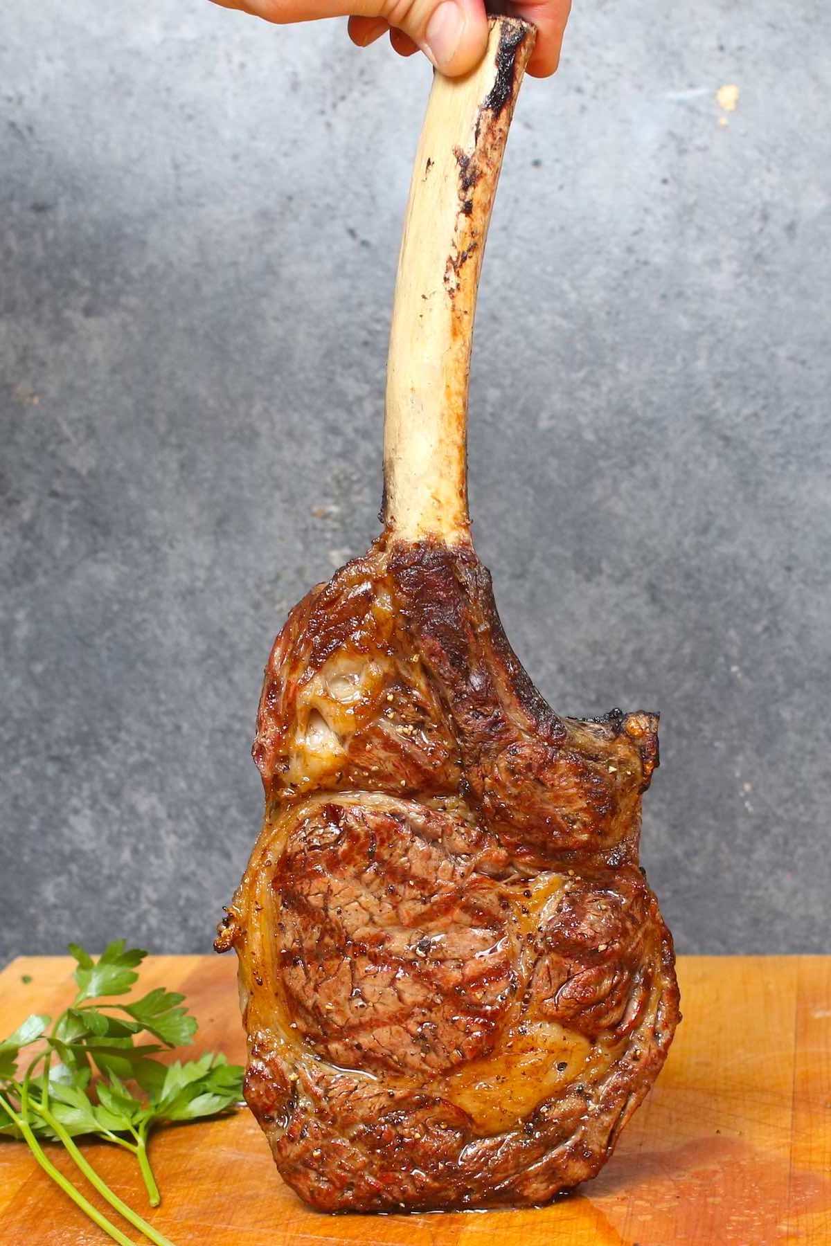 Grilled tomahawk ribeye steak showing crosshatch grill marks and an extra-long bone
