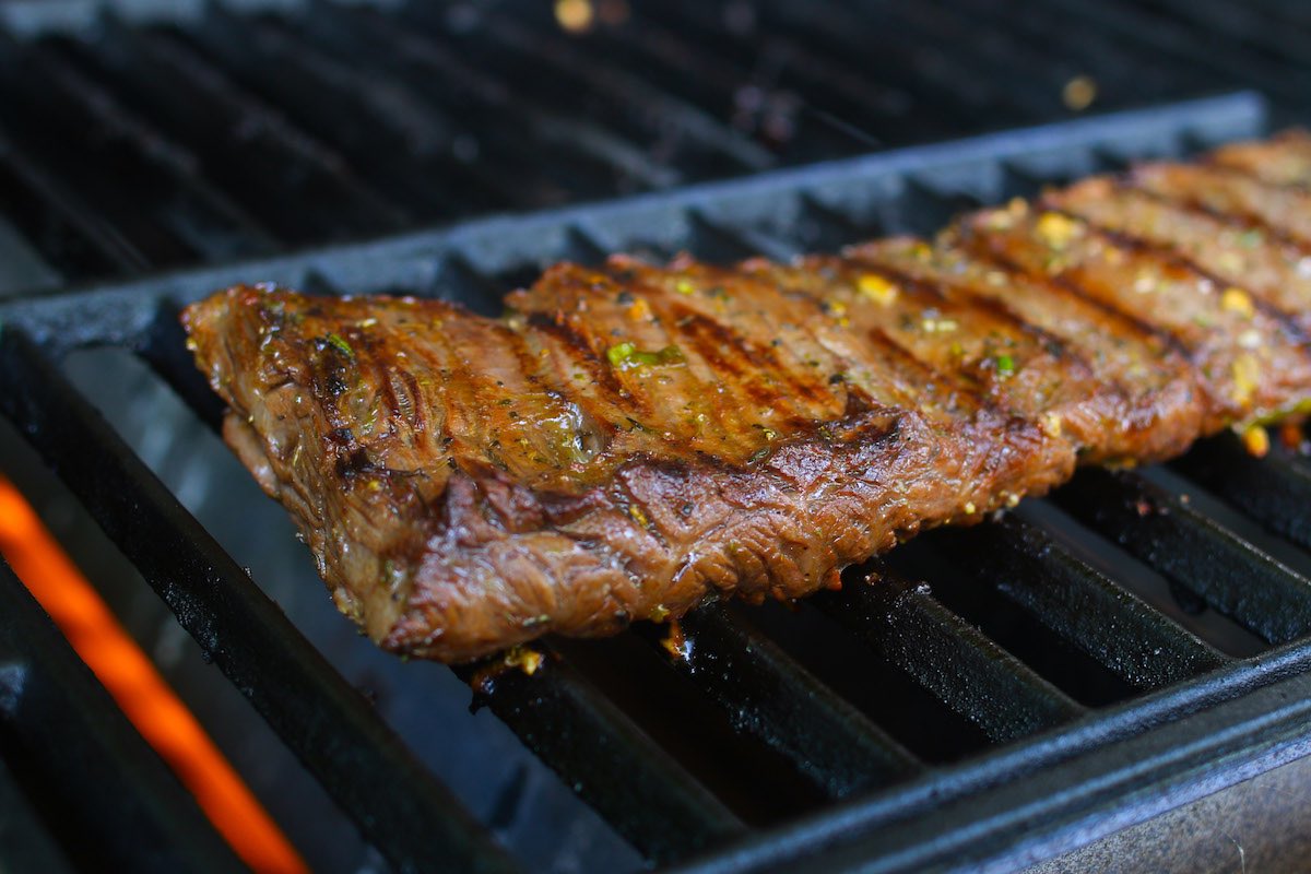 Grilling marinated skirt steak on direct heat to sear the meat while creating beautiful grill marks on the meat