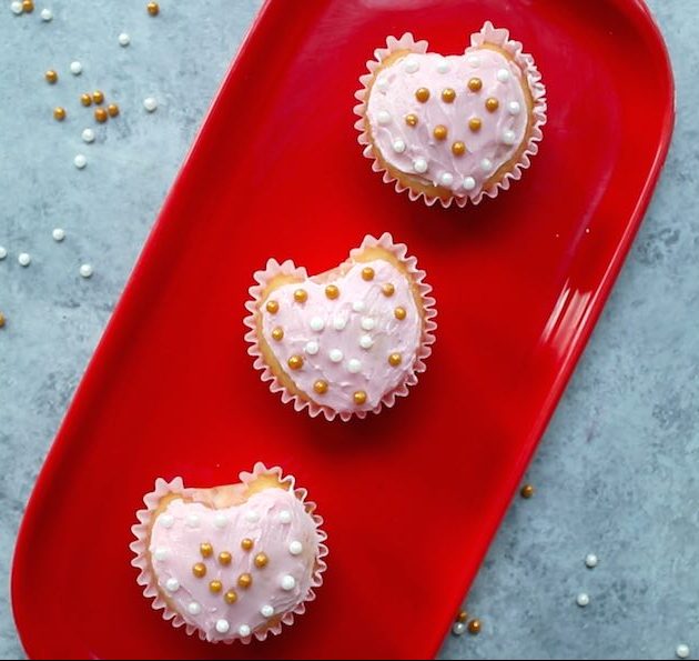 Beautiful Heart Shaped Cupcakes with pink frosting and nonpareil sprinkles on a red platter