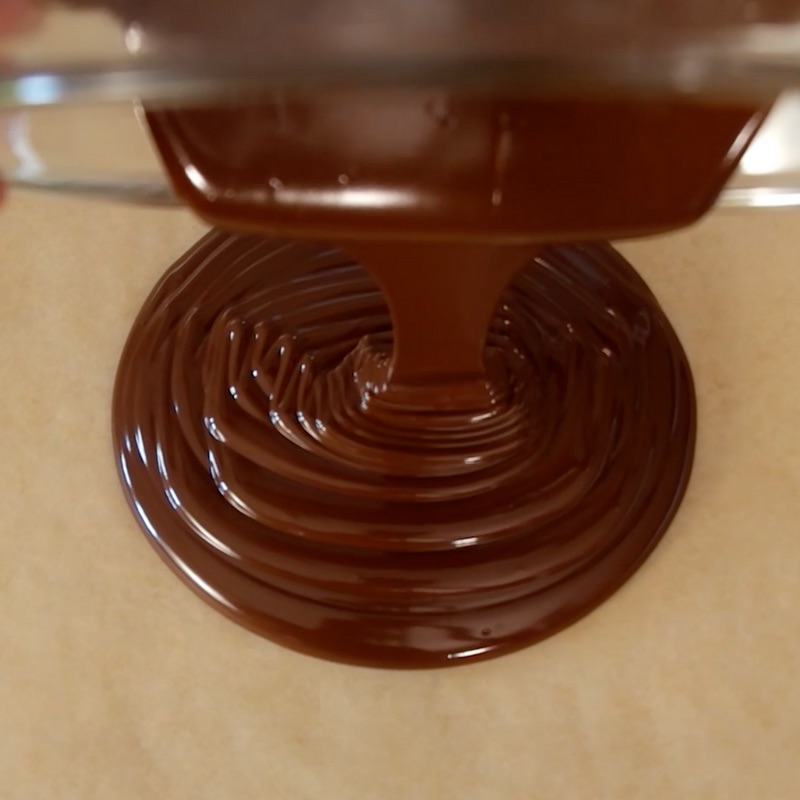 This photo shows how to pour melted chocolate onto a baking sheet to make Chocolate Bark