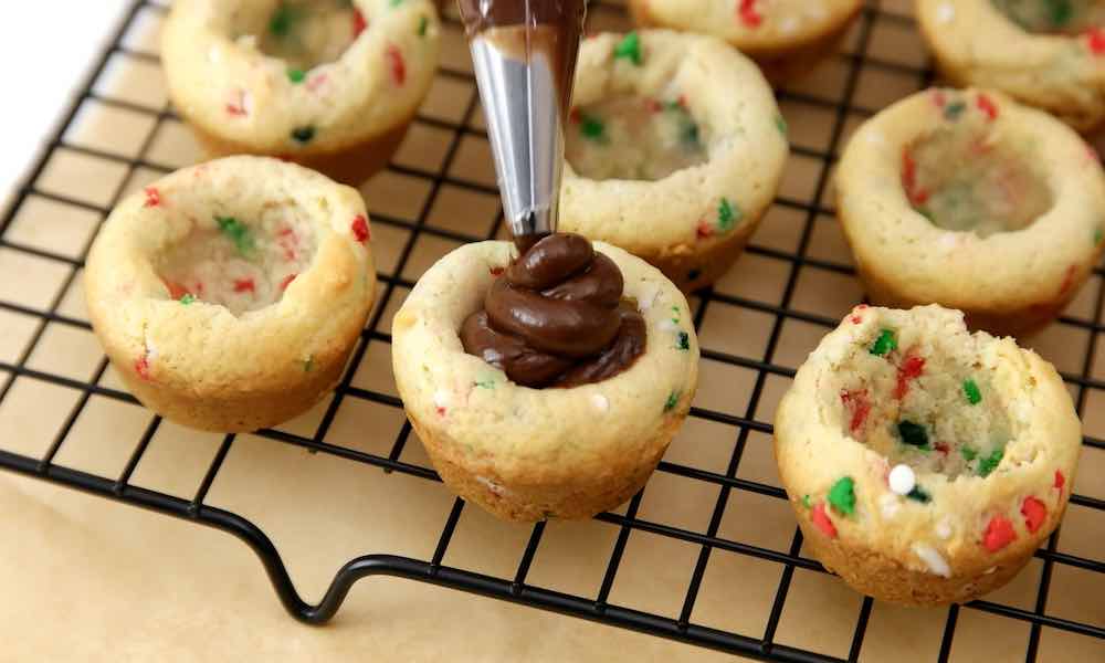 Piping chocolate fudge filling into sugar cookies