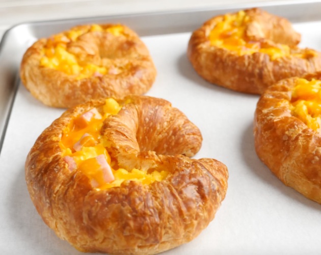 This photo shows Holiday Croissant Boats on a baking sheet coming out of the oven with melted cheese on top