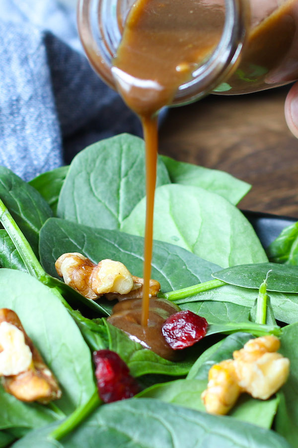 Homemade Balsamic Vinaigrette Dressing being poured onto a spinach salad with walnuts and cranberries for a delicious entree or side dish