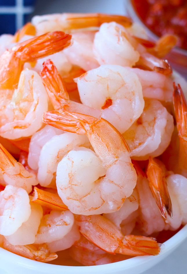 Medium-size, peeled, tail-on shrimp in a bowl after boiling with a beautiful orange-pink color