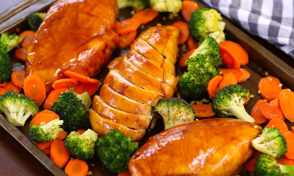 Perfectly cooked chicken breasts on a sheet pan with broccoli and carrots