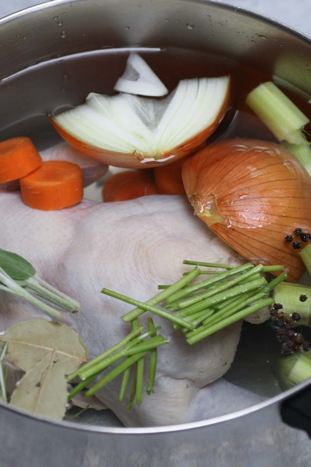 Getting ready to boil chicken in a large pot with fresh vegetables and seasonings