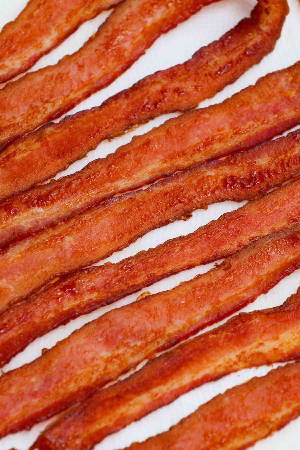 Learn how long to cook bacon in the oven at any temperature including 400, 350 and 375 degrees. Whether you’ve got regular or thick cut, you can make crispy bacon easily by using a parchment-lined pan with or without a rack. It’s a great way to feed a crowd!