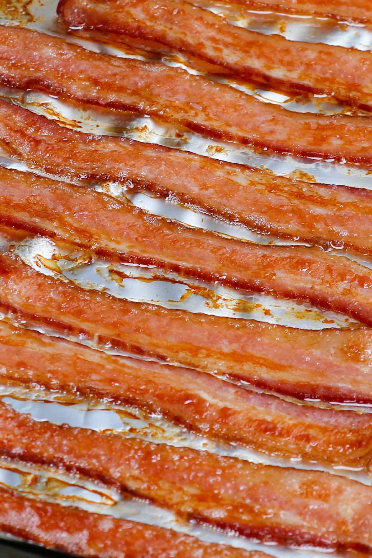 Learn how long to cook bacon in the oven at any temperature including 400, 350 and 375 degrees. Whether you’ve got regular or thick cut, you can make crispy bacon easily by using a parchment-lined pan with or without a rack. It’s a great way to feed a crowd!