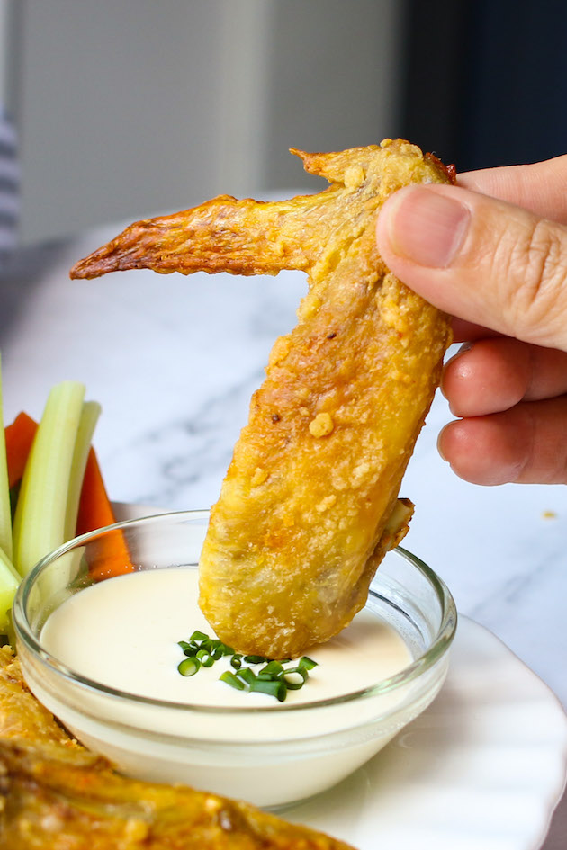Learn how to bake chicken wings and get crispy wings like this one being dipped in ranch