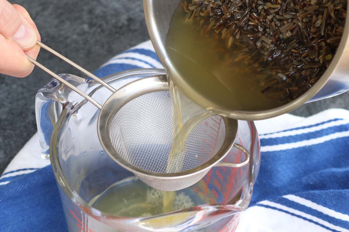 Draining excess water from the pot after cooking with the help of a strainer