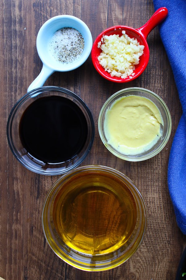 The ingredients for making balsamic vinaigrette: balsamic vinegar, extra virgin olive oil, dijon mustard, minced garlic, salt and pepper