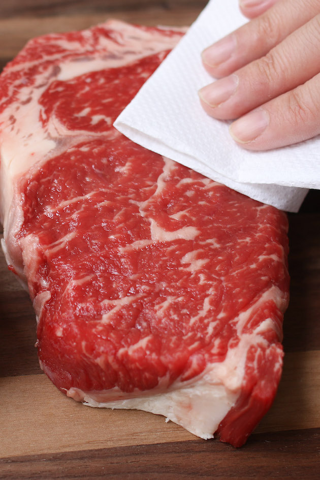 This photo shows the first step in broiling steak, which is to pat it dry with paper towel to remove excess moisture.