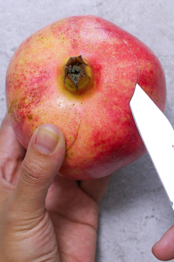 Cutting open the top of the pomegranate, also called the blossom, using a paring knife