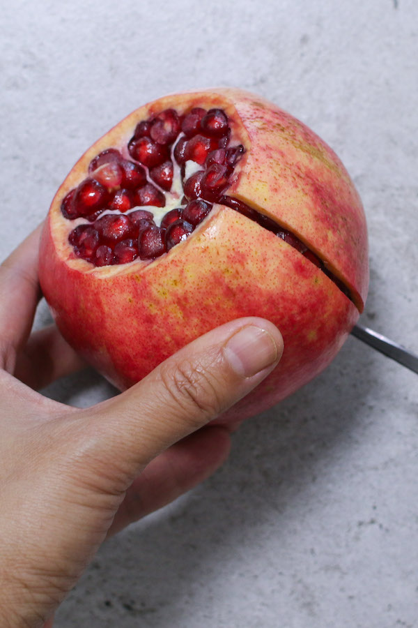 Scoring the peel of the pomegranate with a paring knife when cutting a pomegranate