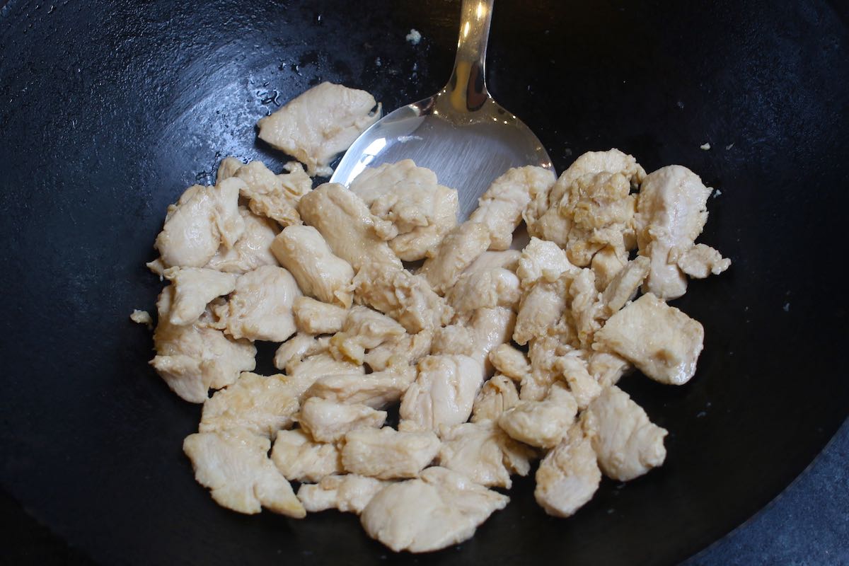 Par-cooking marinated chicken in a wok when making Hunan Chicken