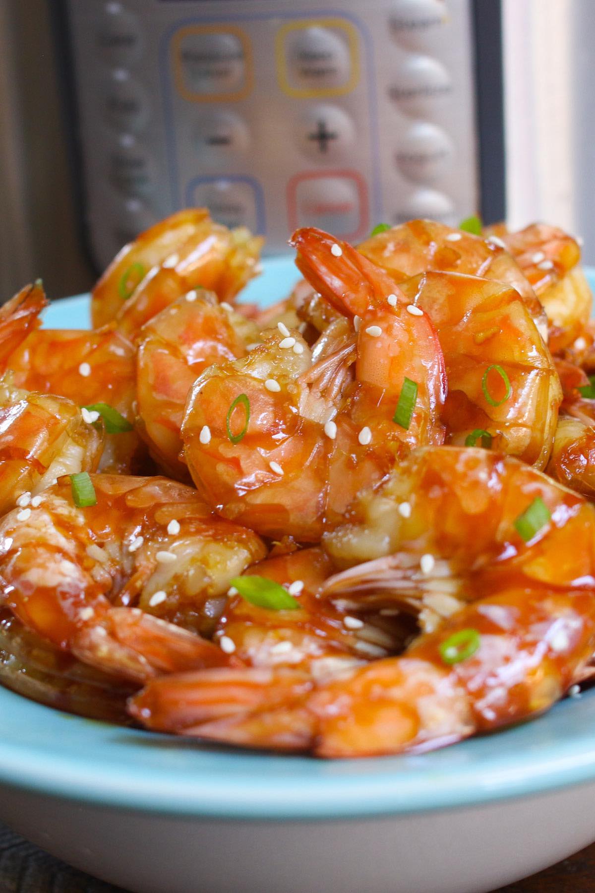 Instant Pot Shrimp with honey garlic sauce garnished with minced green onion and sesame seeds on a serving plate