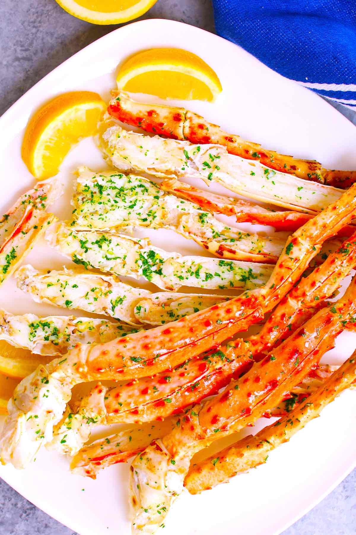King crab legs served on a white plate with lemon wedges.