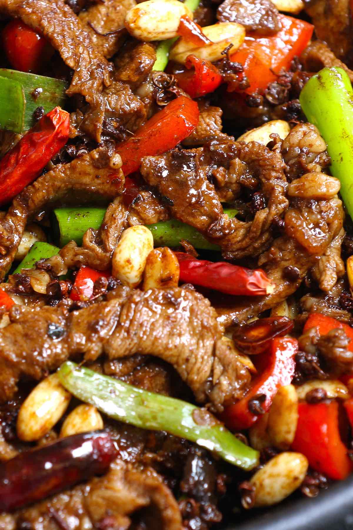 Closeup of Szechuan beef with bell peppers, peanuts and chilis