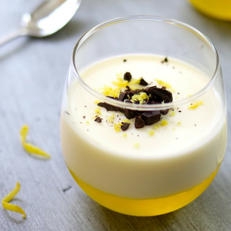 Lemon Panna Cotta in a stemless wine glass garnished with lemon zest and crushed chocolate