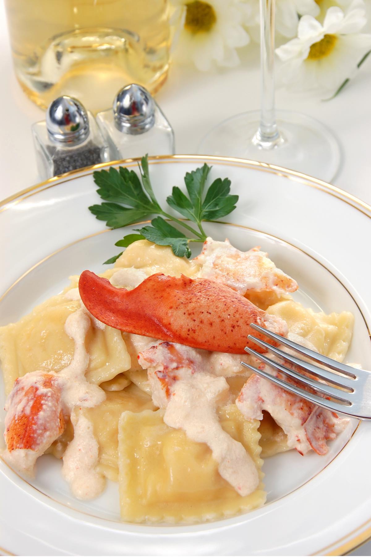 A serving of lobster ravioli with a rose-colored cream sauce and garnished with fresh lobster meat