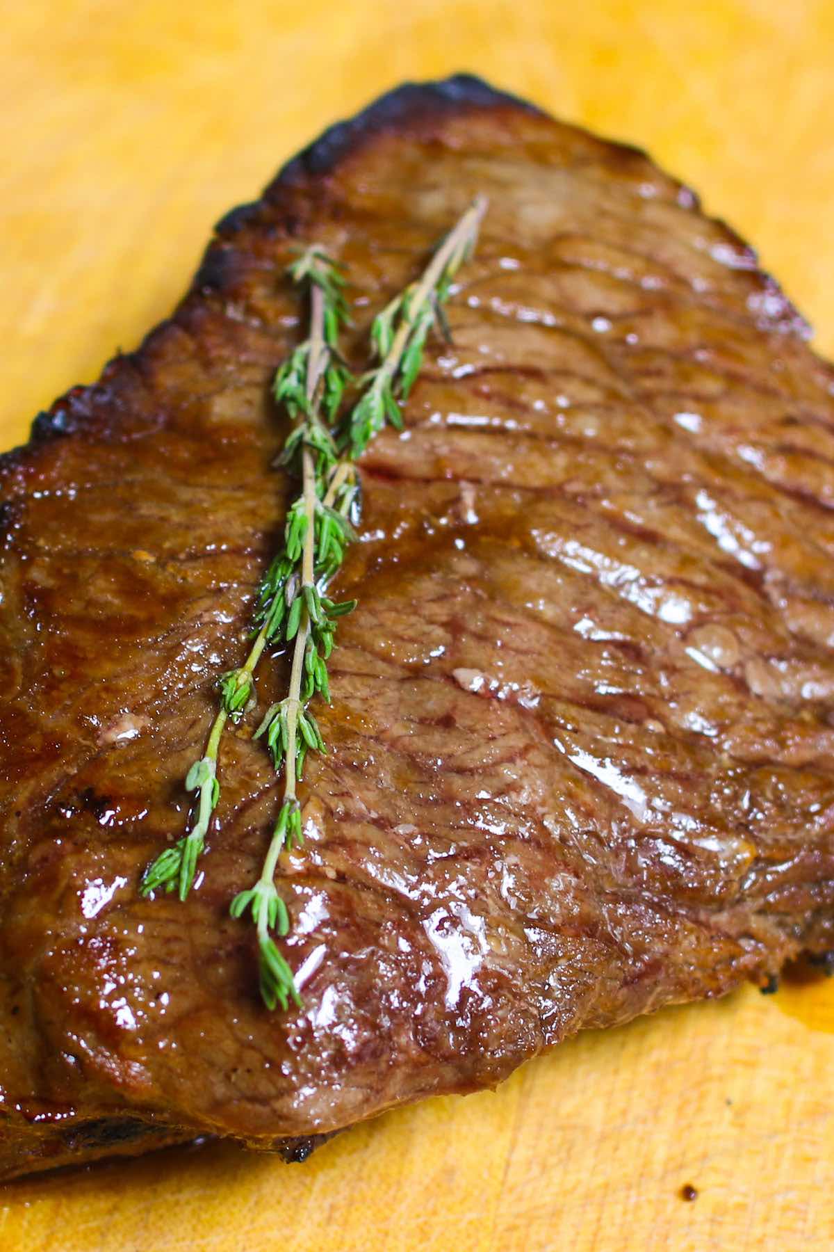 London Broil made with top round fresh out of the oven showing caramelization on the outside and garnished with sprigs of fresh thyme