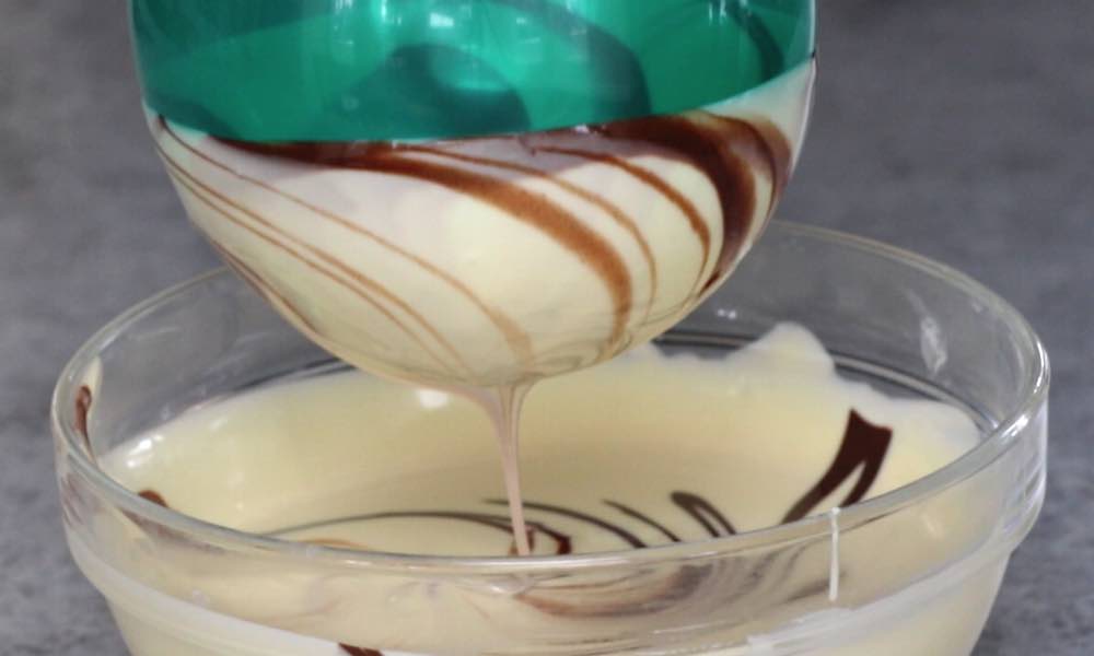 Dipping a balloon into two types of melted chocolate to create a swirl pattern