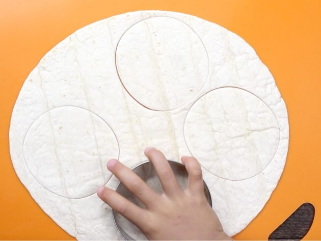 Process photo of making circular cutouts from flour tortillas to bake into salad cups