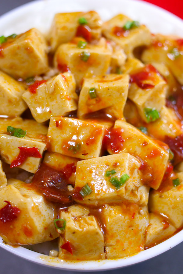 Mapo Tofu served in a rice bowl and topped with crushed szechuan peppercorns and minced green onion