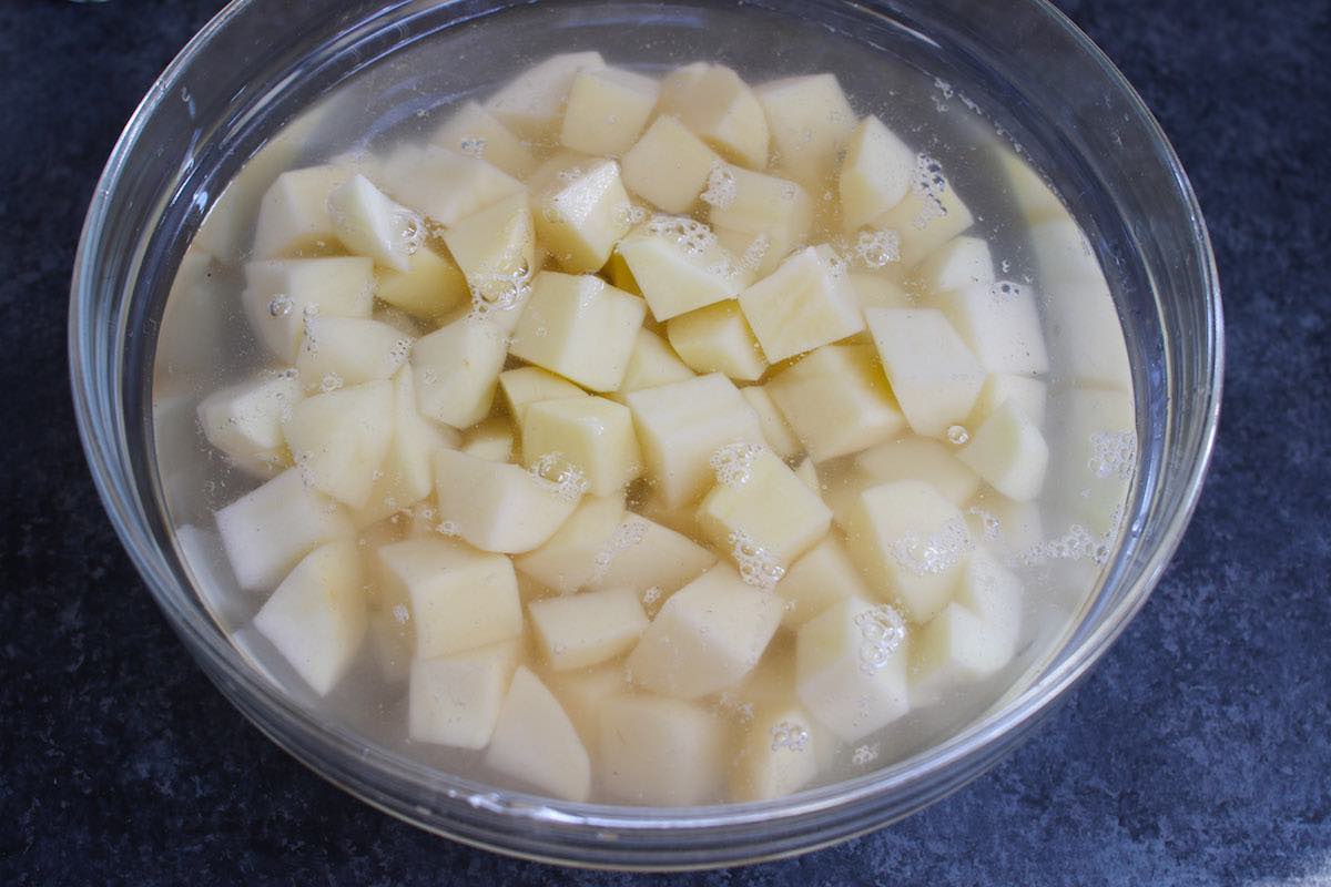 Cubed potatoes covered in salted water for up to 12 hours to prevent oxidation and discoloration
