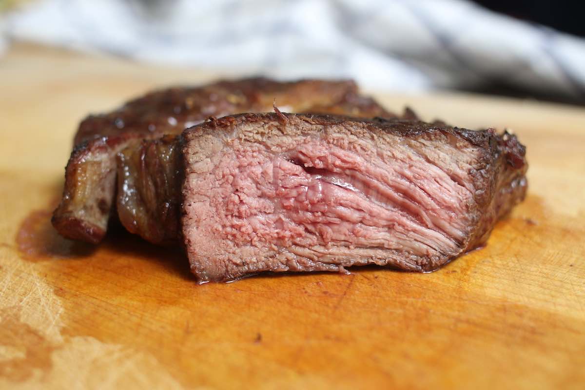 Closeup of steak grilled to medium well doneness showing a charred exterior and pale pink interior