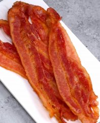 Find out how long to microwave bacon, whether you’ve got regular or thick-cut bacon. Learn how to cook bacon using a microwave bacon cooker or just paper towels and a plate. It’s fast and produces delicious crispy bacon with easy cleanup!