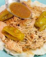 Spooning juices from the slow cooker onto the shredded chicken