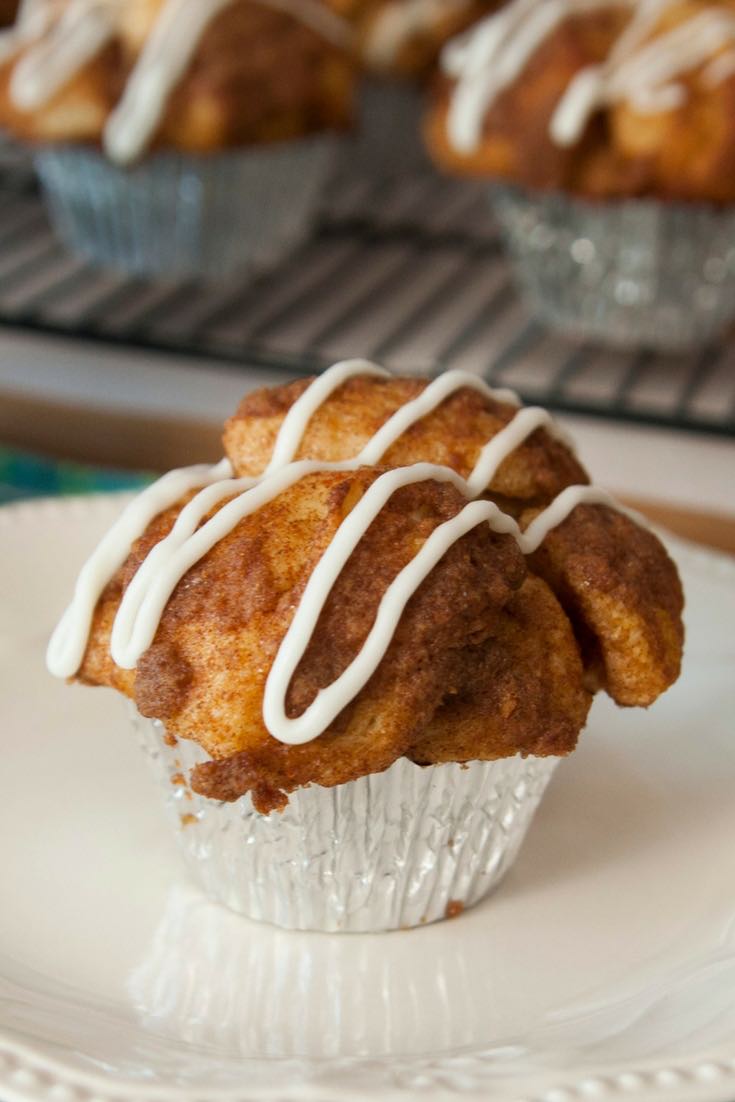 A freshly baked monkey bread muffin on a serving plate with icing drizzled on top