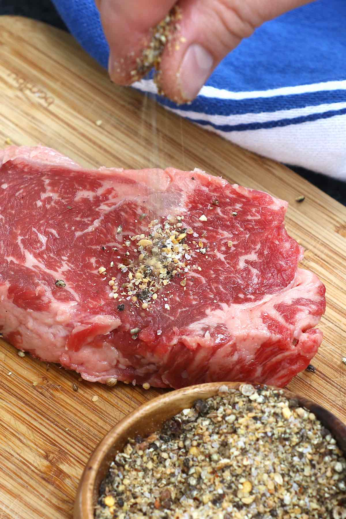 Adding Montreal steak spice to a raw striploin steak