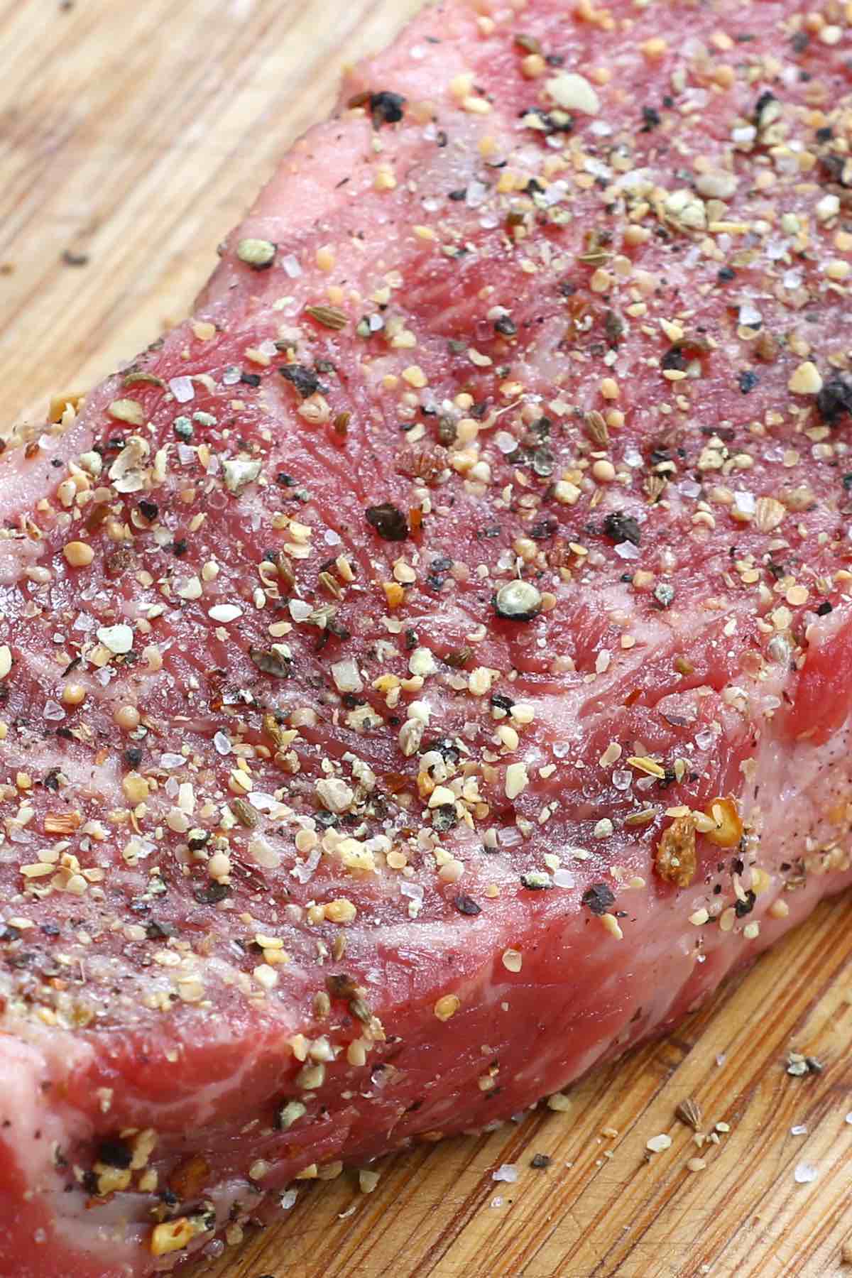A striploin steak that has been rubbed with Montreal seasoning and is ready for cooking