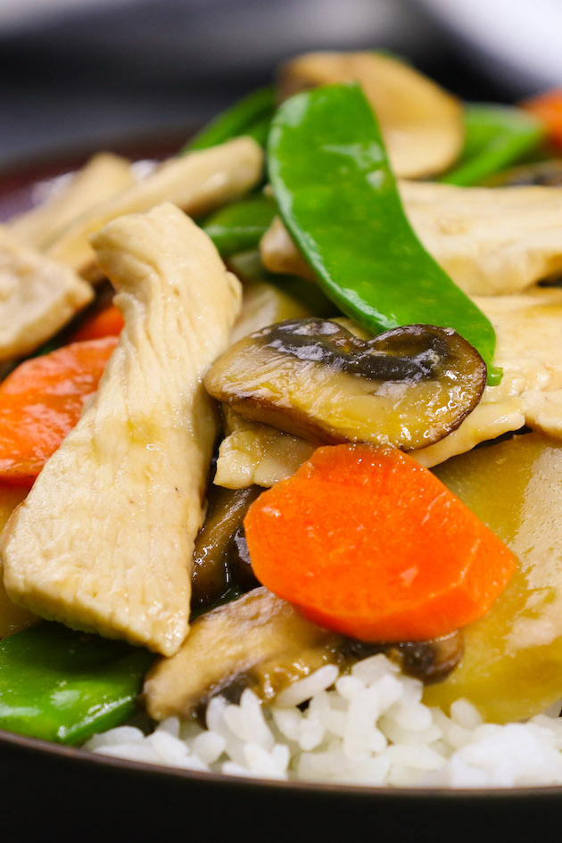 Moo Goo Gai Pan served over rice in a black bowl.