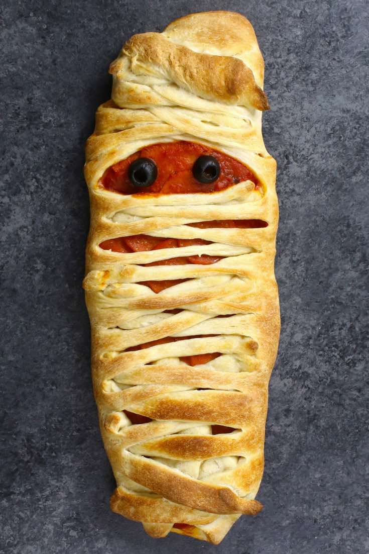 A mummy pizza made with pepperoni and olives for eyes