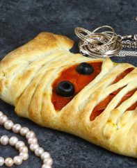A mummy pizza with jewels for decoration