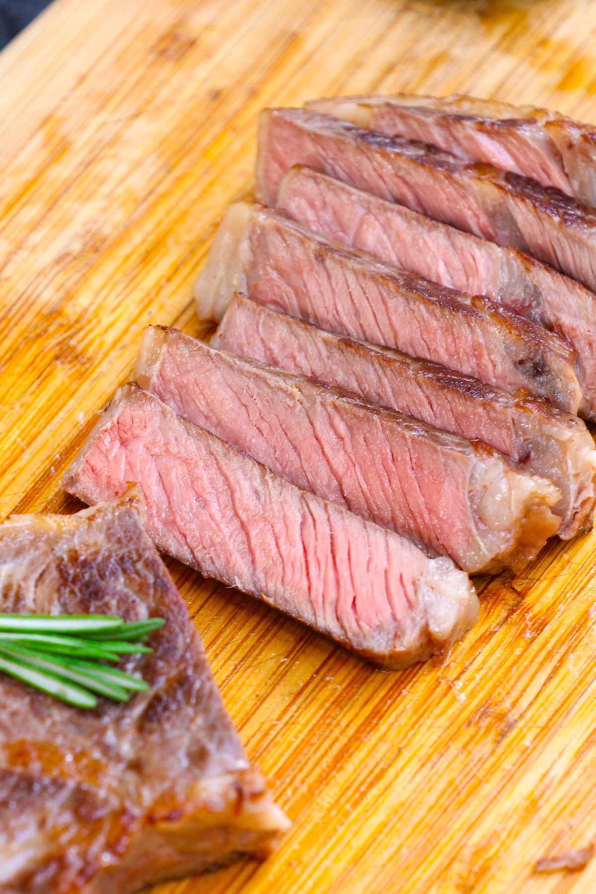 Slices of New York strip on a carving board showing a pale pink color