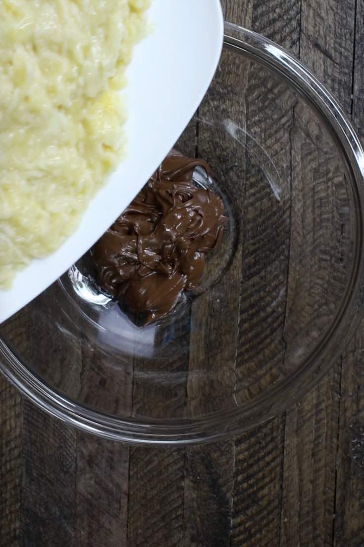 Adding mashed bananas to Nutella in a mixing bowl