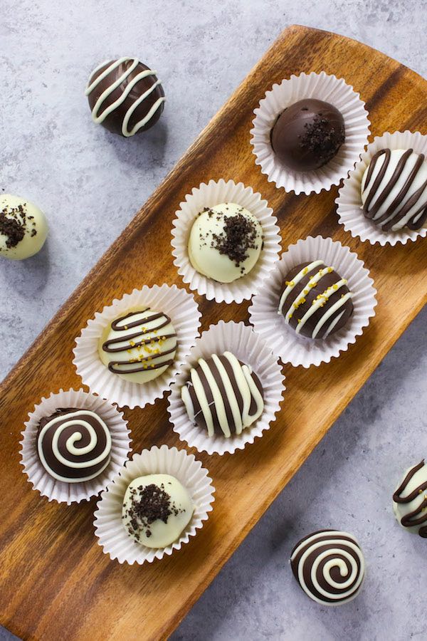 A serving platter of beautiful Oreo truffles decorated with chocolate drizzle in different patterns and oreo powder